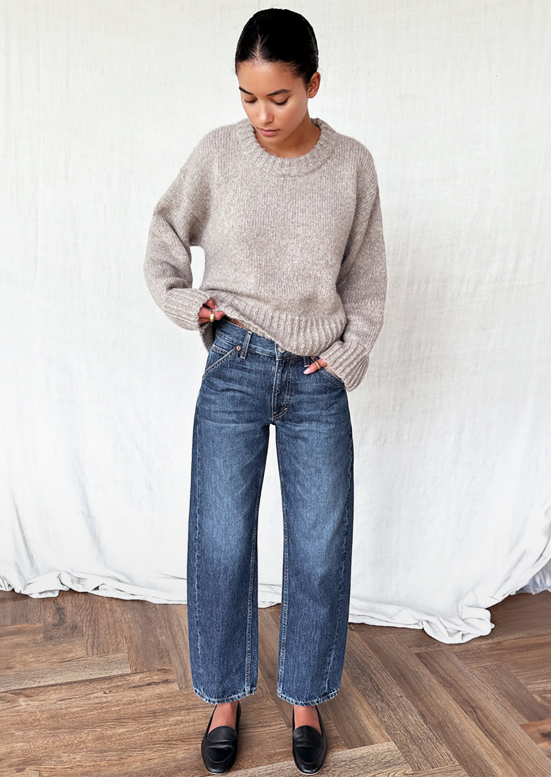 A woman wearing a round neck sweater with ribbed hem and cuffs.