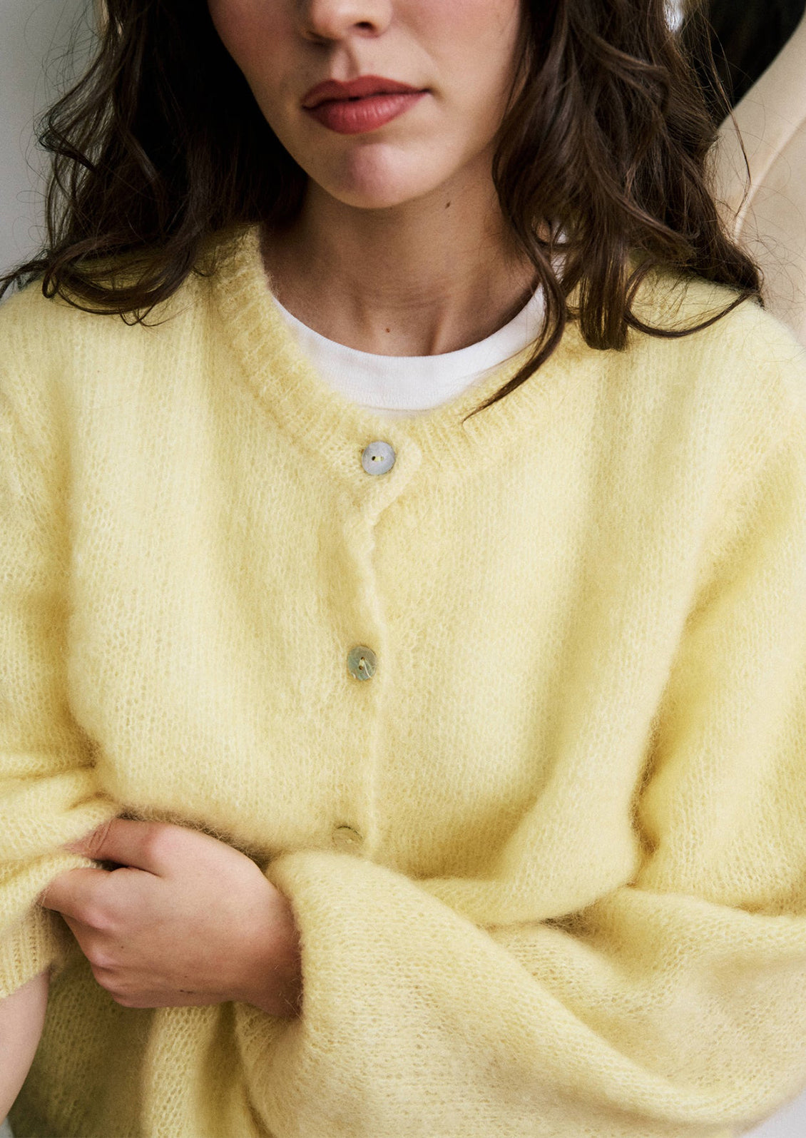 A woman wearing a butter yellow button front cardigan mohair sweater.