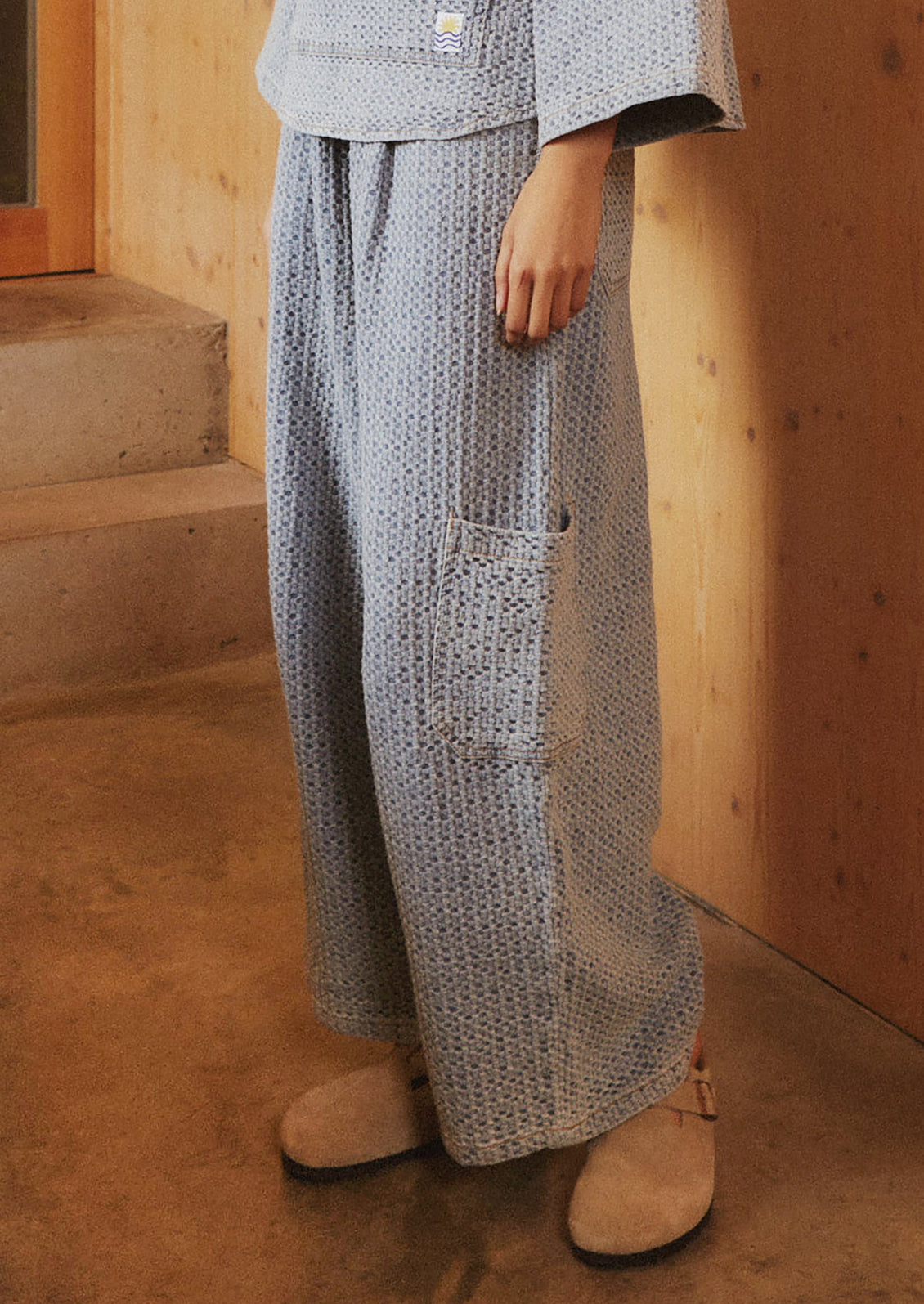A woman wearing a pair of wide leg, seersucker texture pants in light blue.