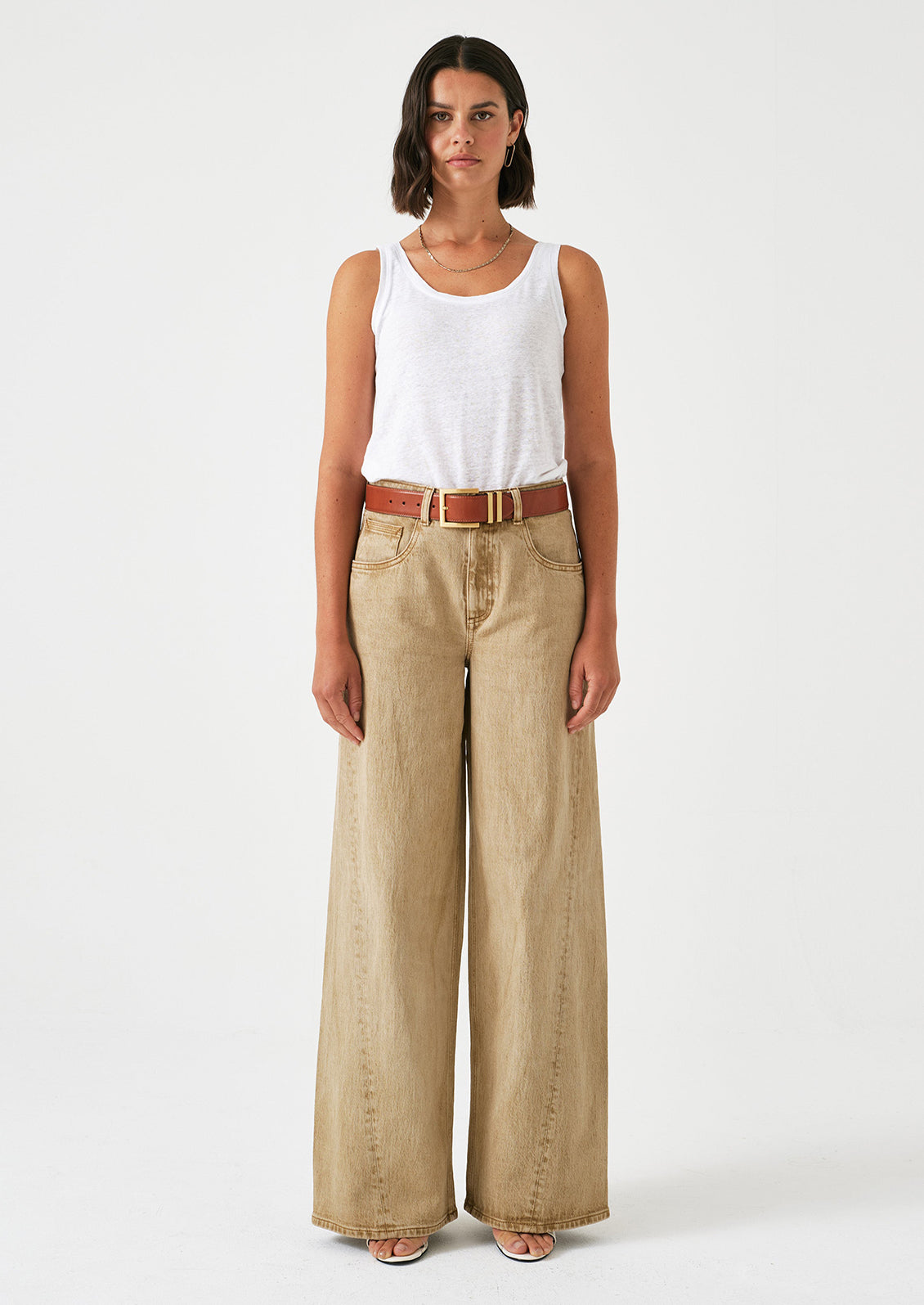 A woman wearing a pair of slouchy wide leg jeans in a stonewashed sand color.