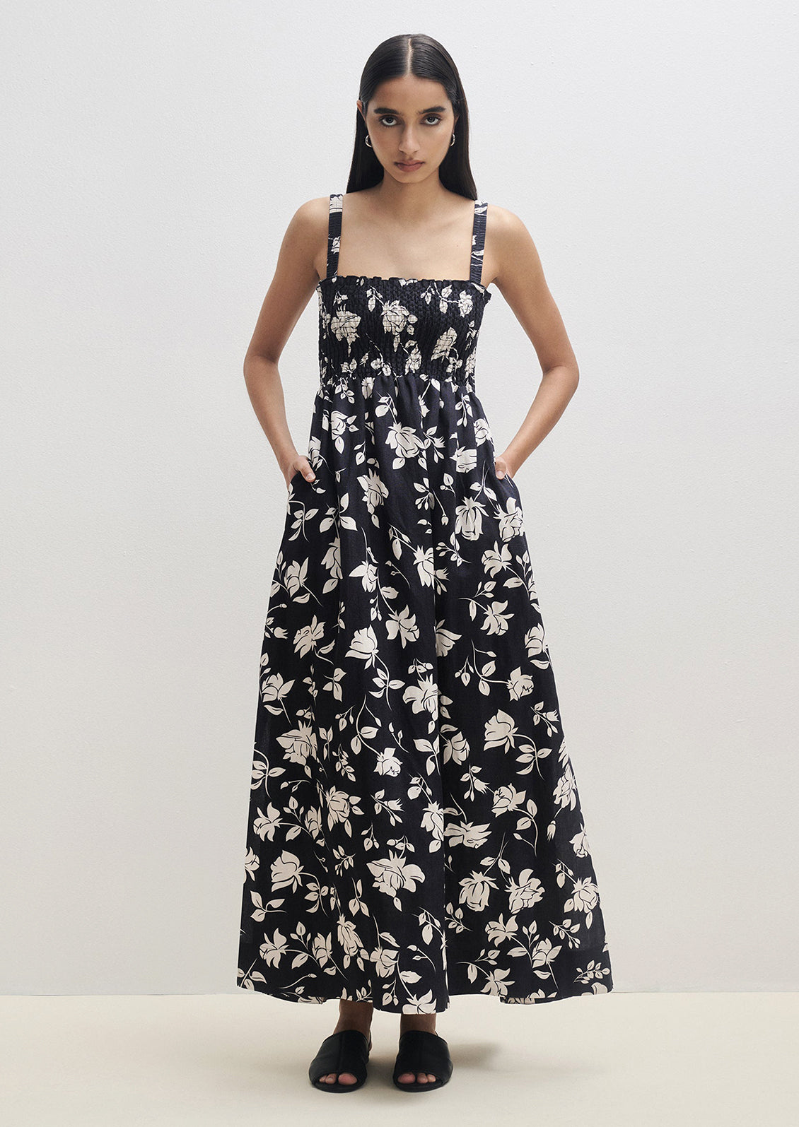 A woman wearing a black and white floral print maxi dress with smocked bodice.
