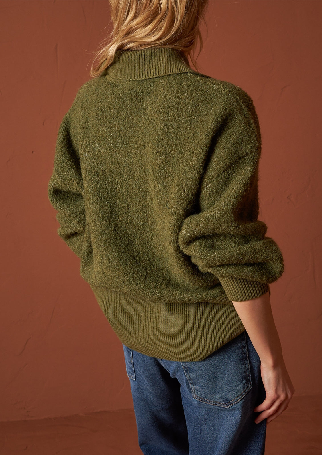 A woman wearing a polo collar fuzzy army green sweater.