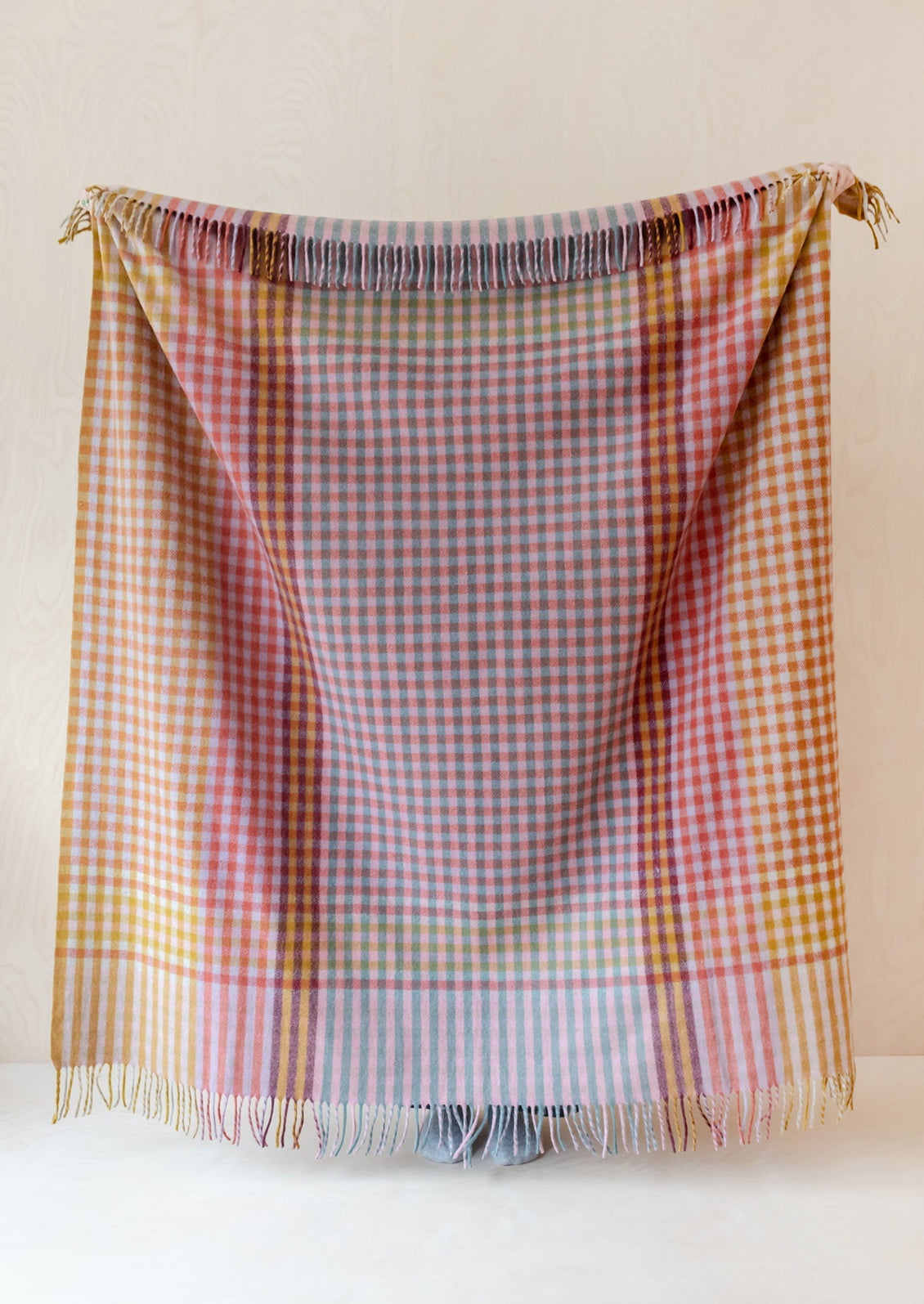 A colorful gingham check blanket in tones of lilac, magenta, and yellow.