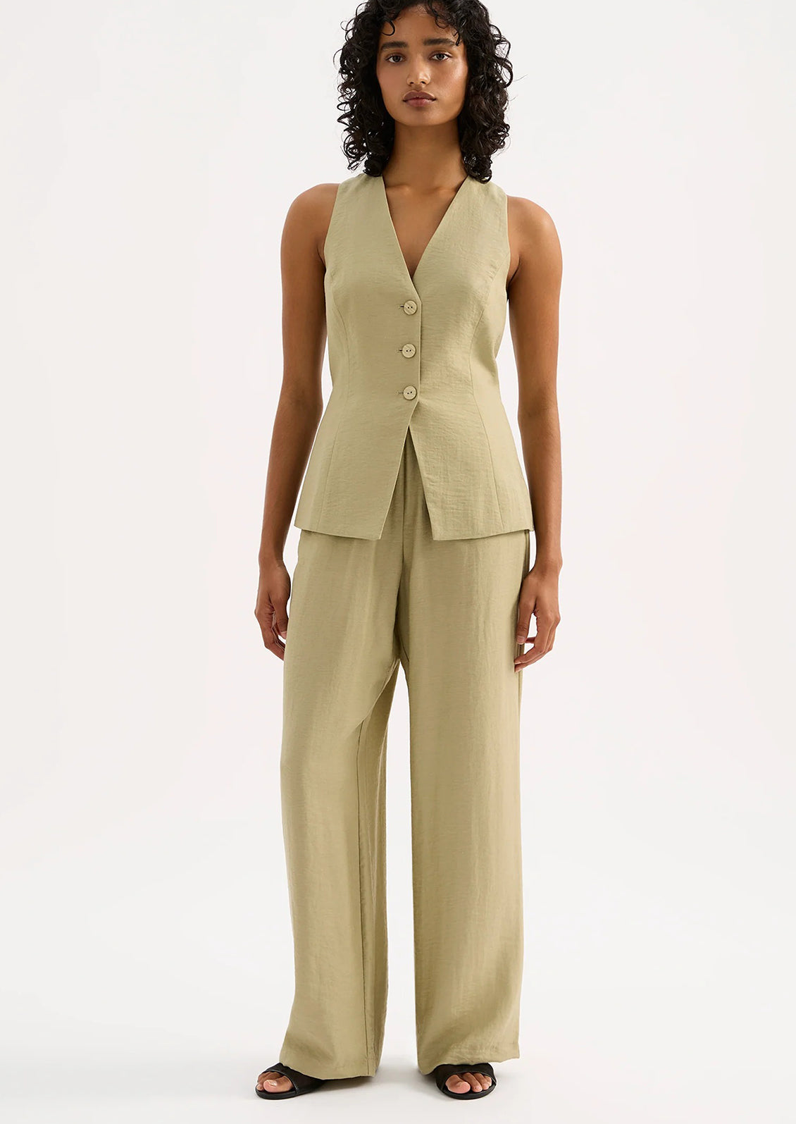 A woman wearing a pair of green suiting pants.