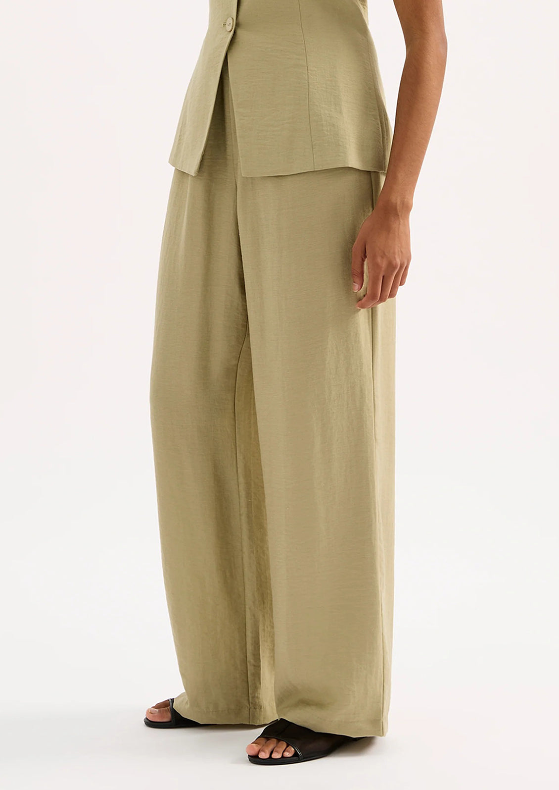 A woman wearing a pair of green suiting pants.