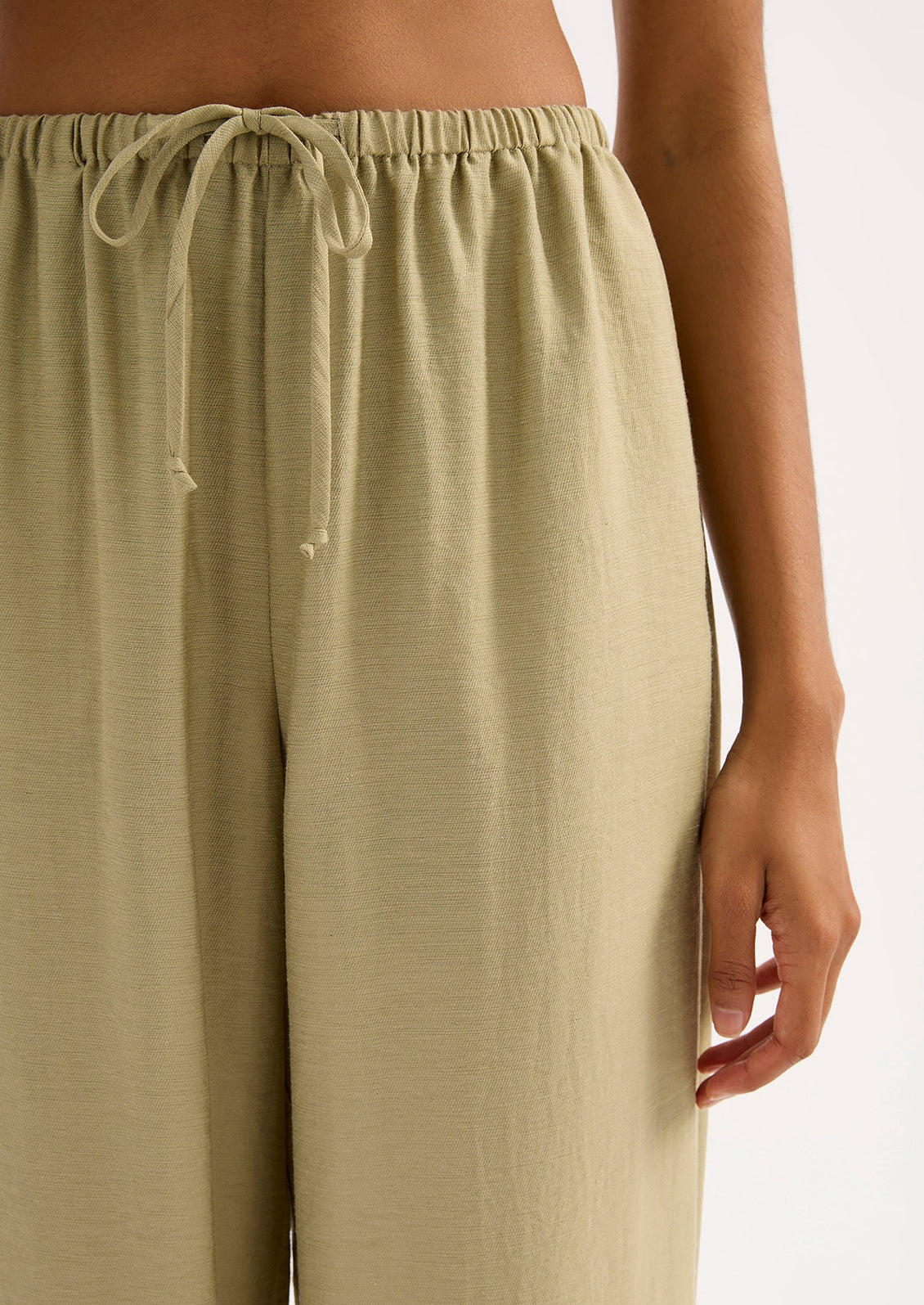 A woman wearing a pair of green suiting pants.