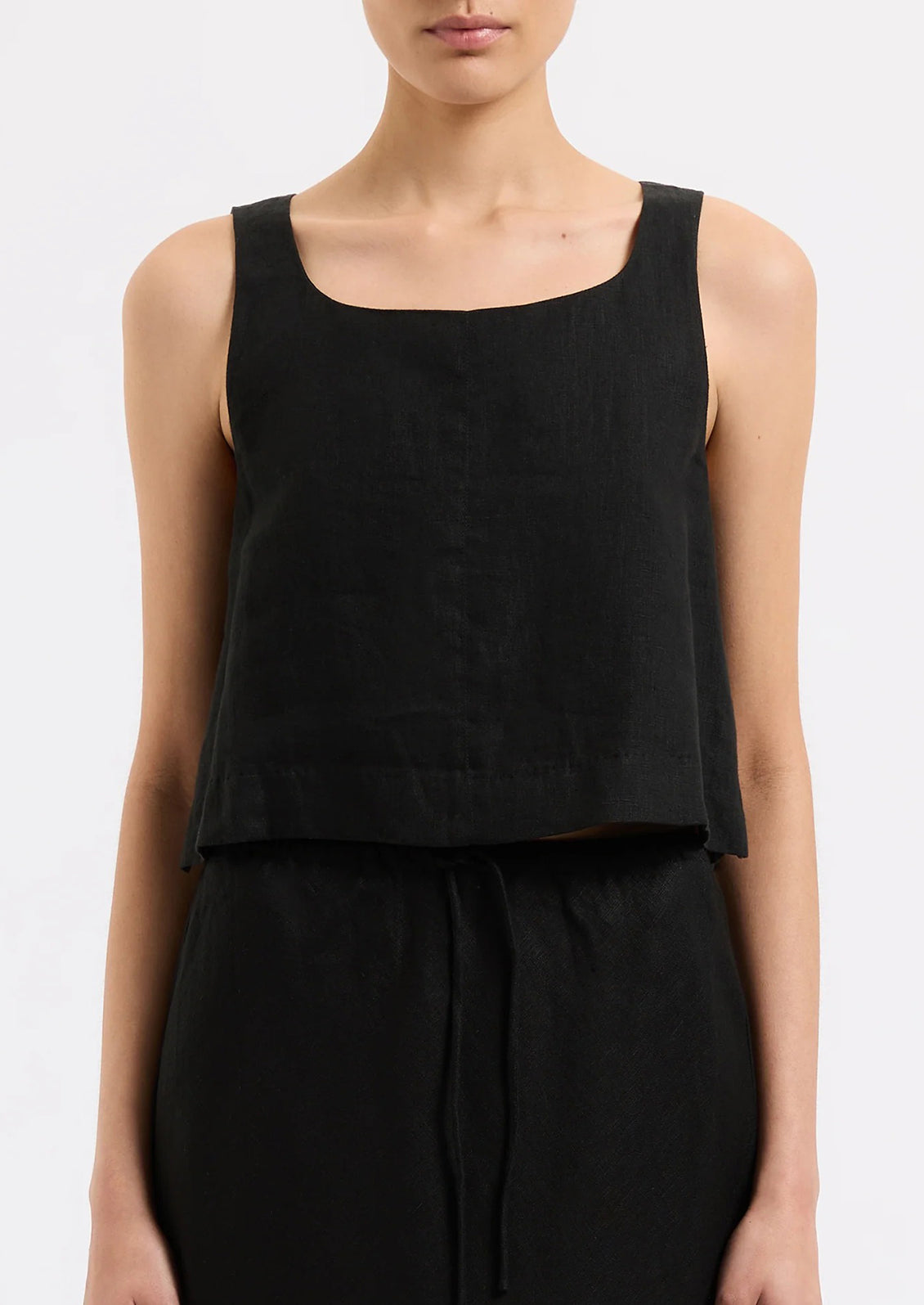 A person wearing a sleeveless shift tank in black.