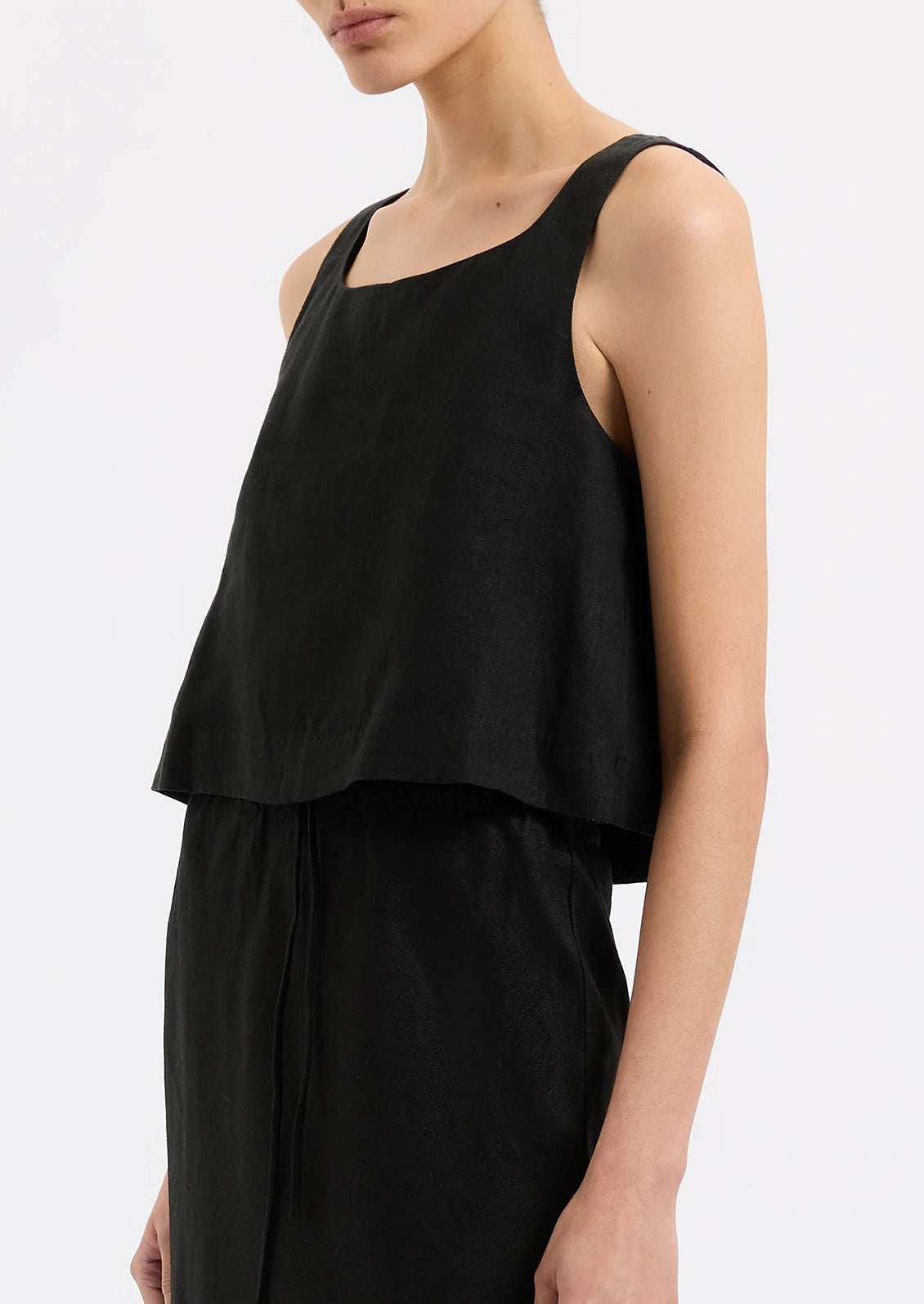 A person wearing a sleeveless shift tank in black.