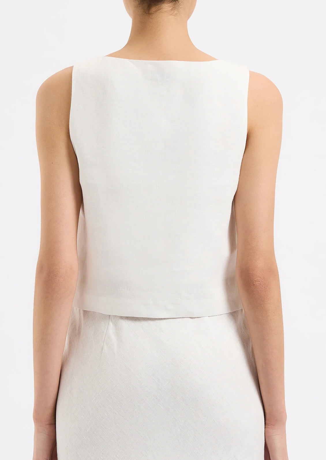 A person wearing a sleeveless shift tank in white.