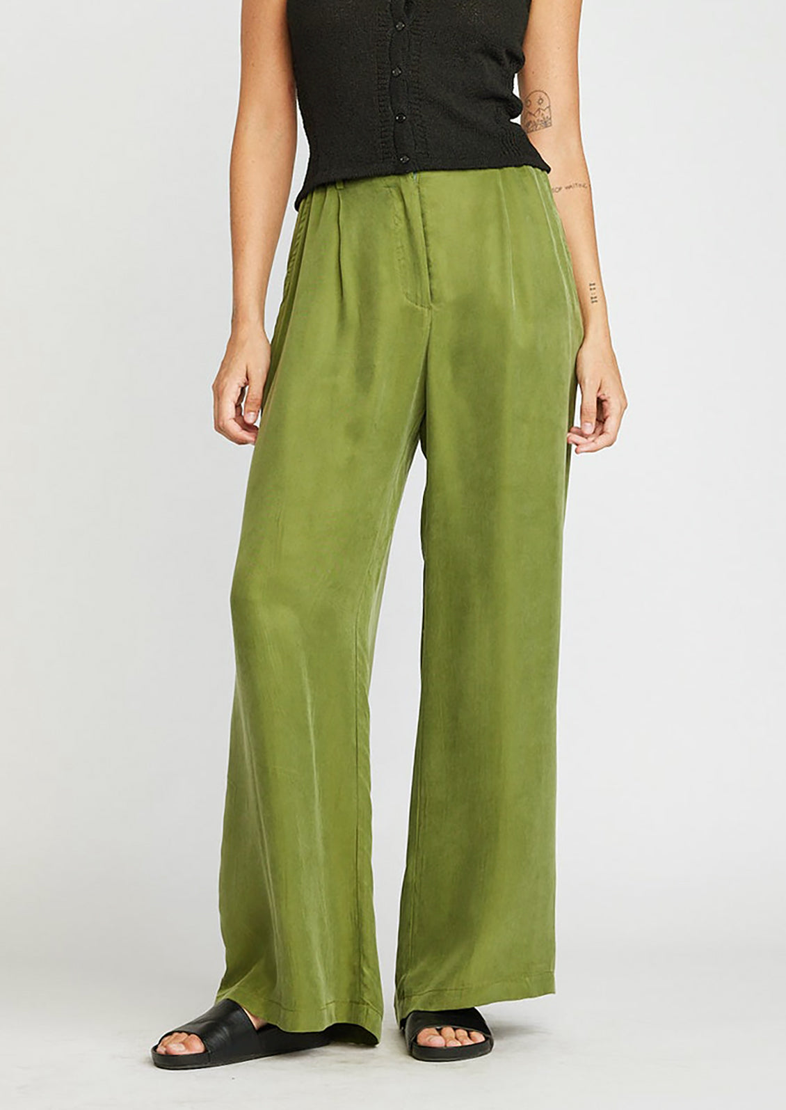 A person wearing a pair of cupro trousers in kelp green.