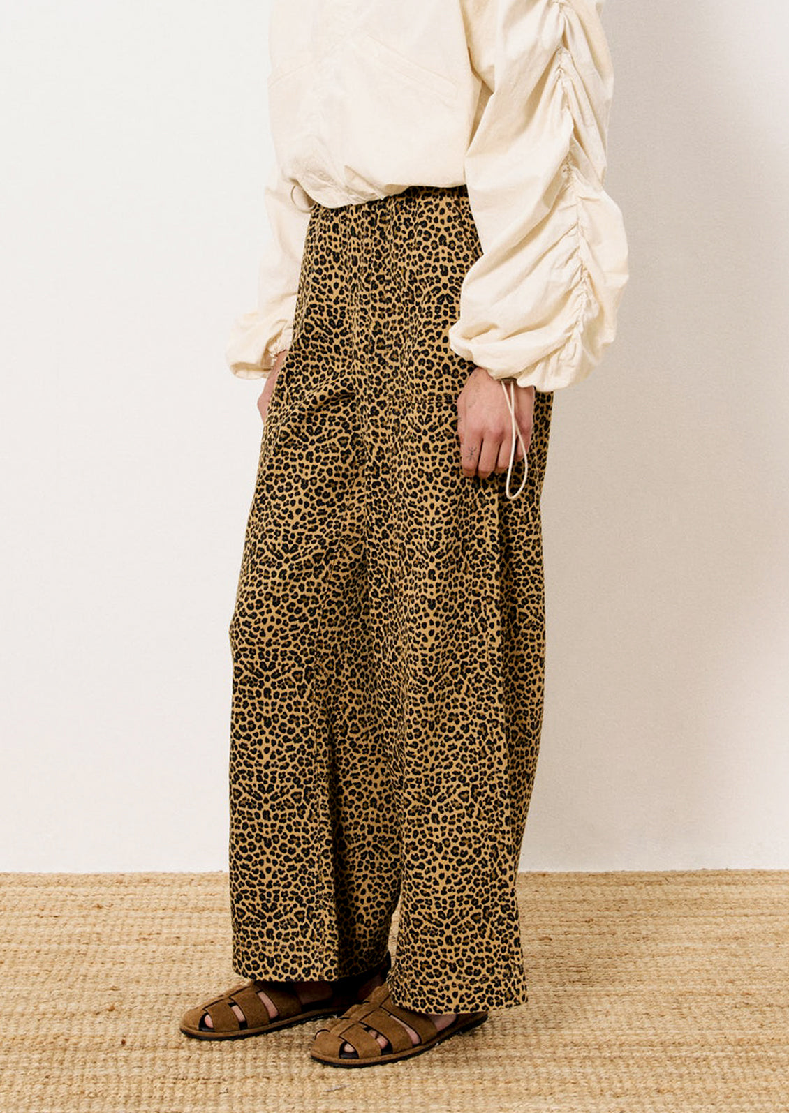 A person wearing a pair of leopard print pants with slightly wide leg.