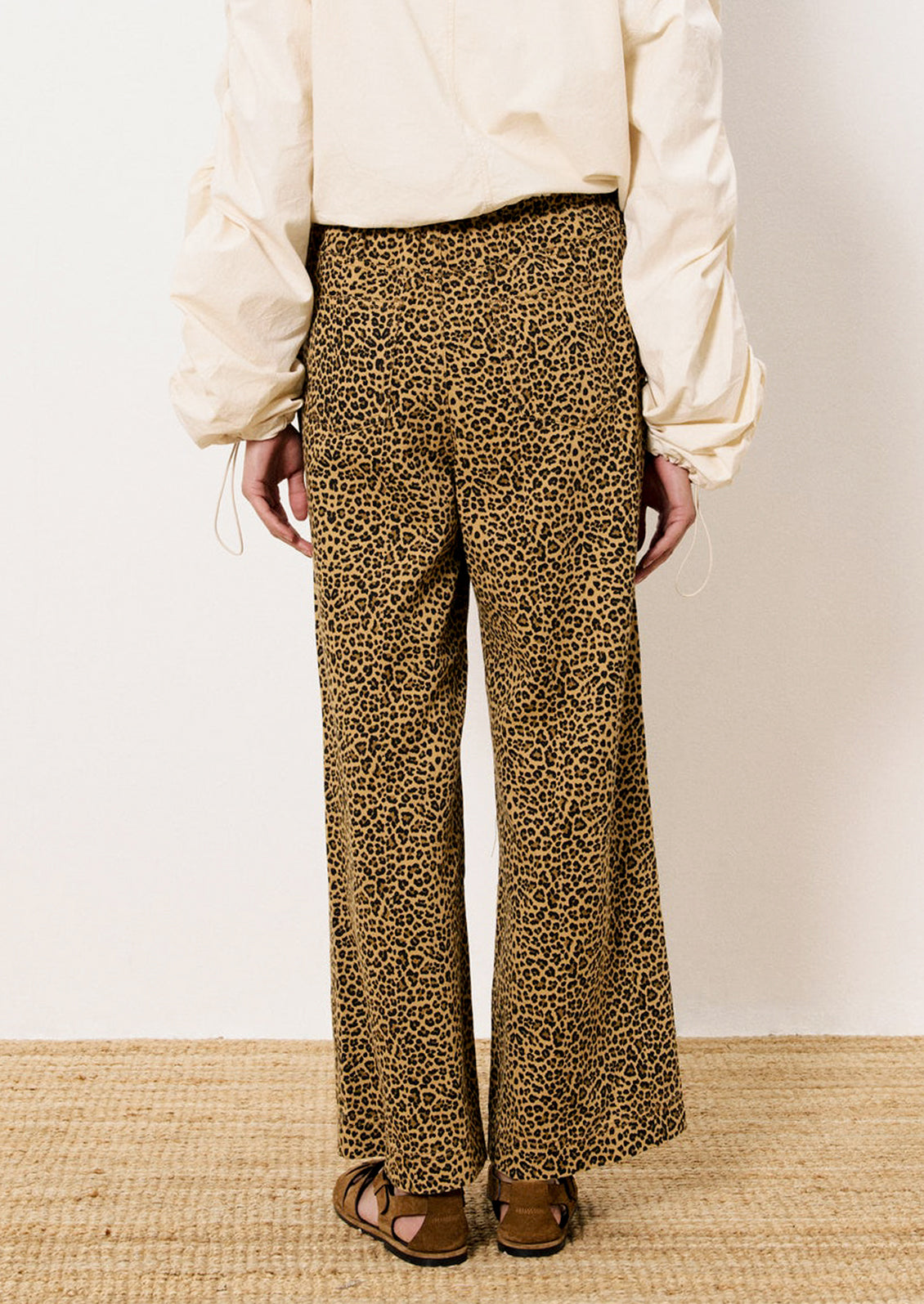 A person wearing a pair of leopard print pants with slightly wide leg.