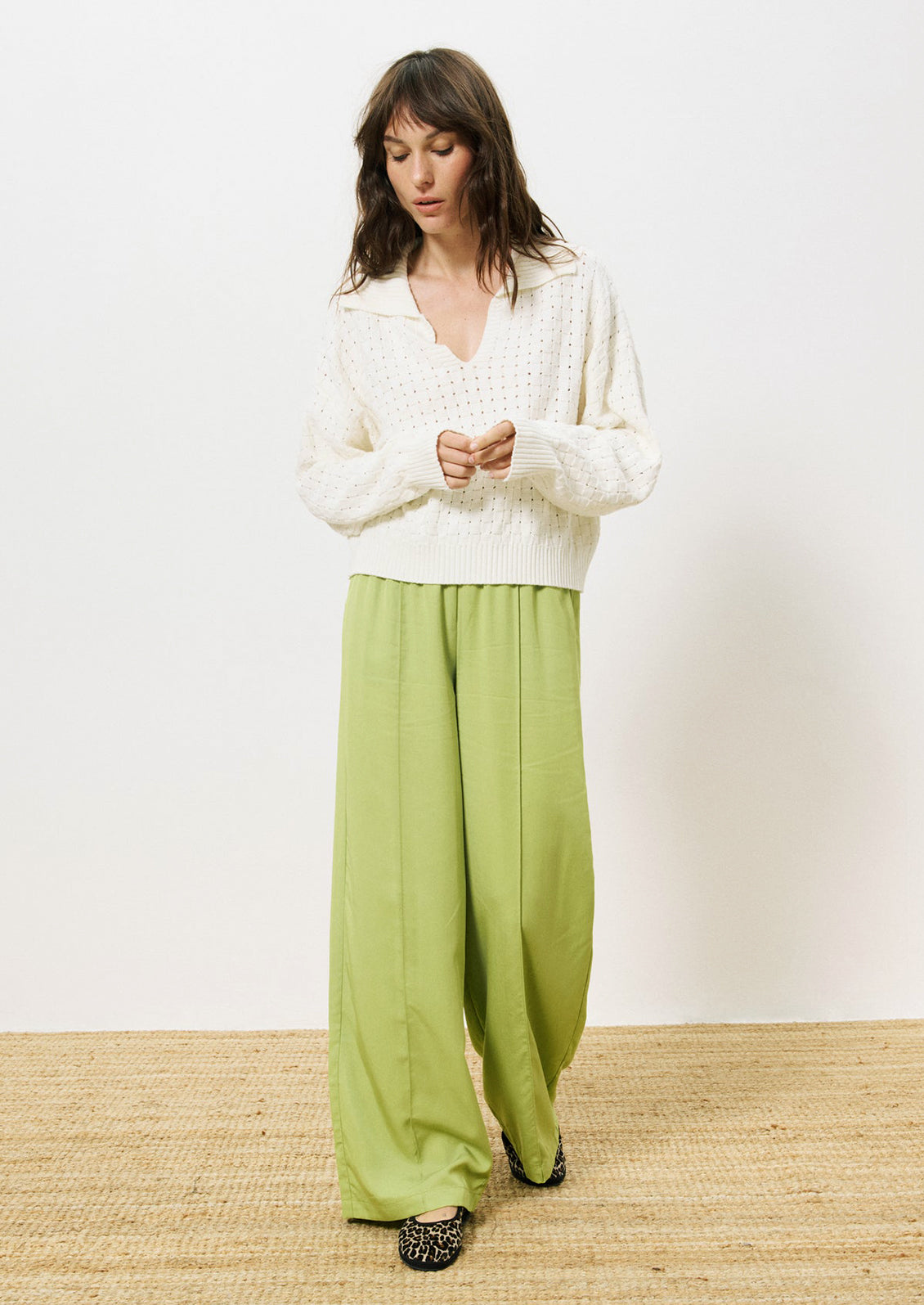 A woman wearing a collared v-neck sweater with woven texture in white.