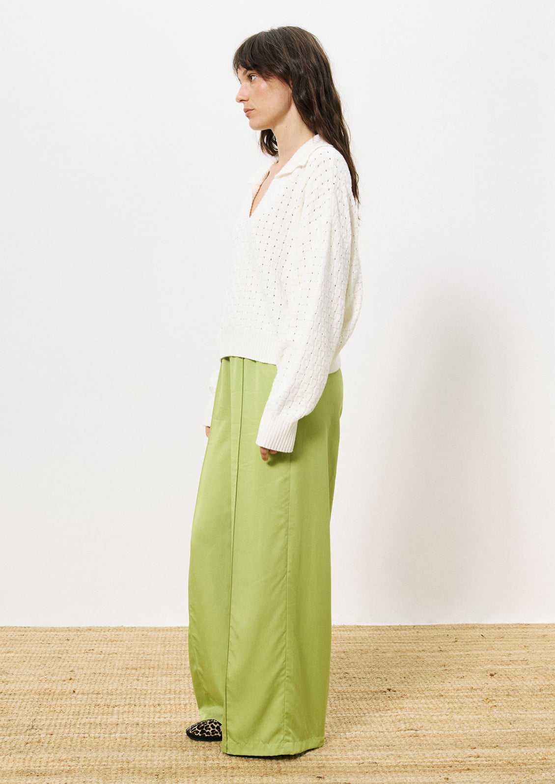 A woman wearing a collared v-neck sweater with woven texture in white.