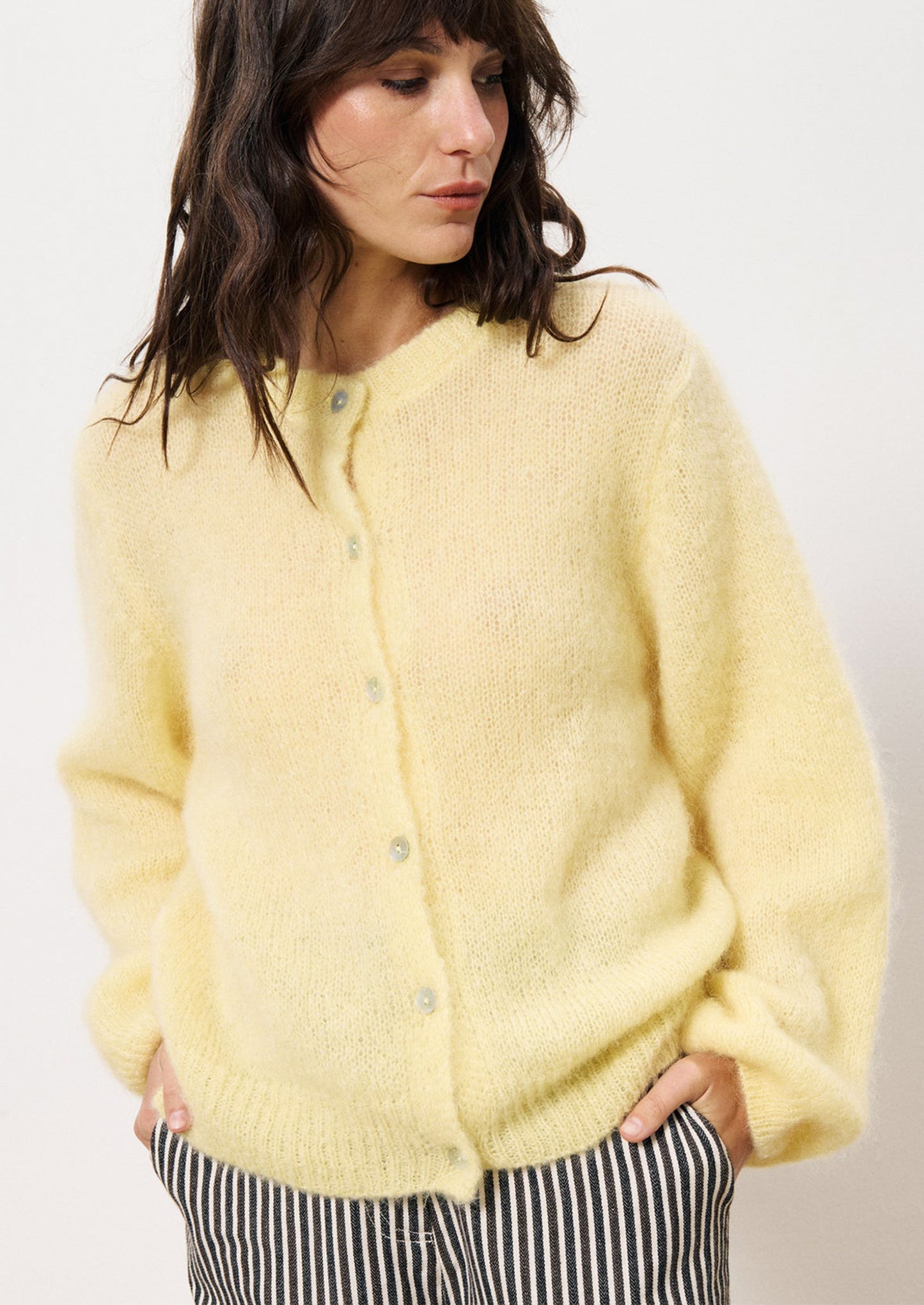 A woman wearing a butter yellow button front cardigan mohair sweater.