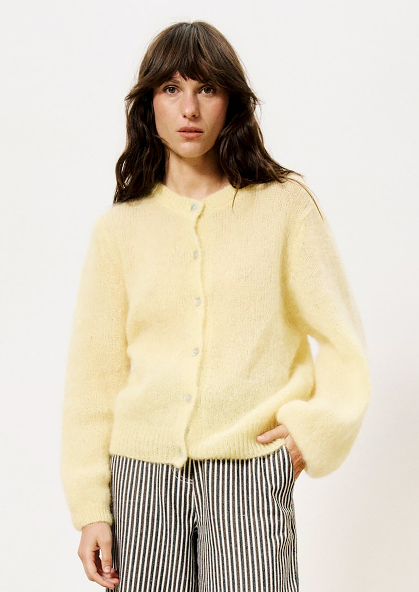 A woman wearing a butter yellow button front cardigan mohair sweater.