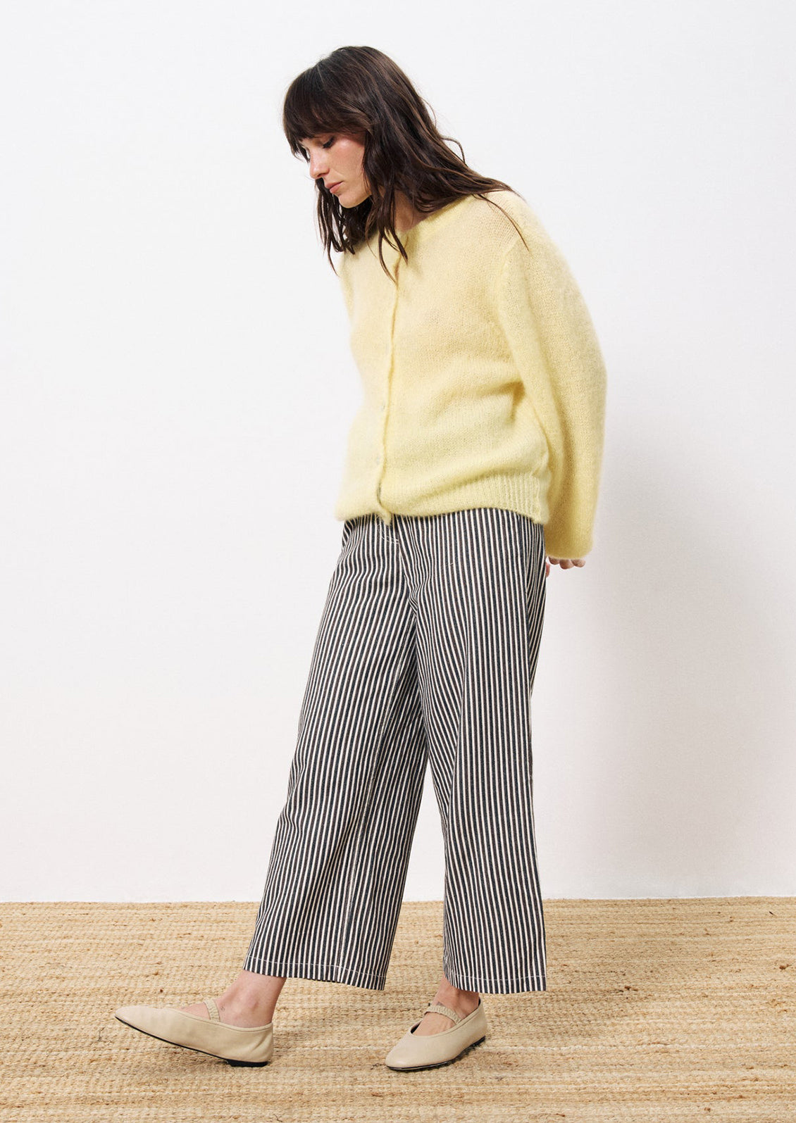 A woman wearing a butter yellow button front cardigan mohair sweater.