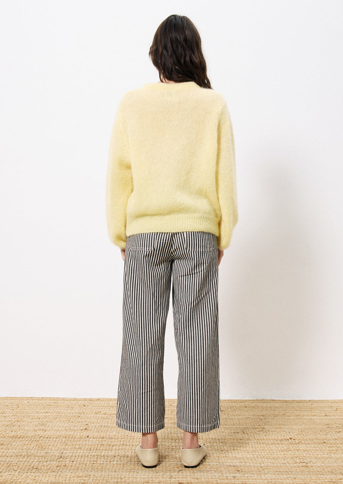 A woman wearing a butter yellow button front cardigan mohair sweater.