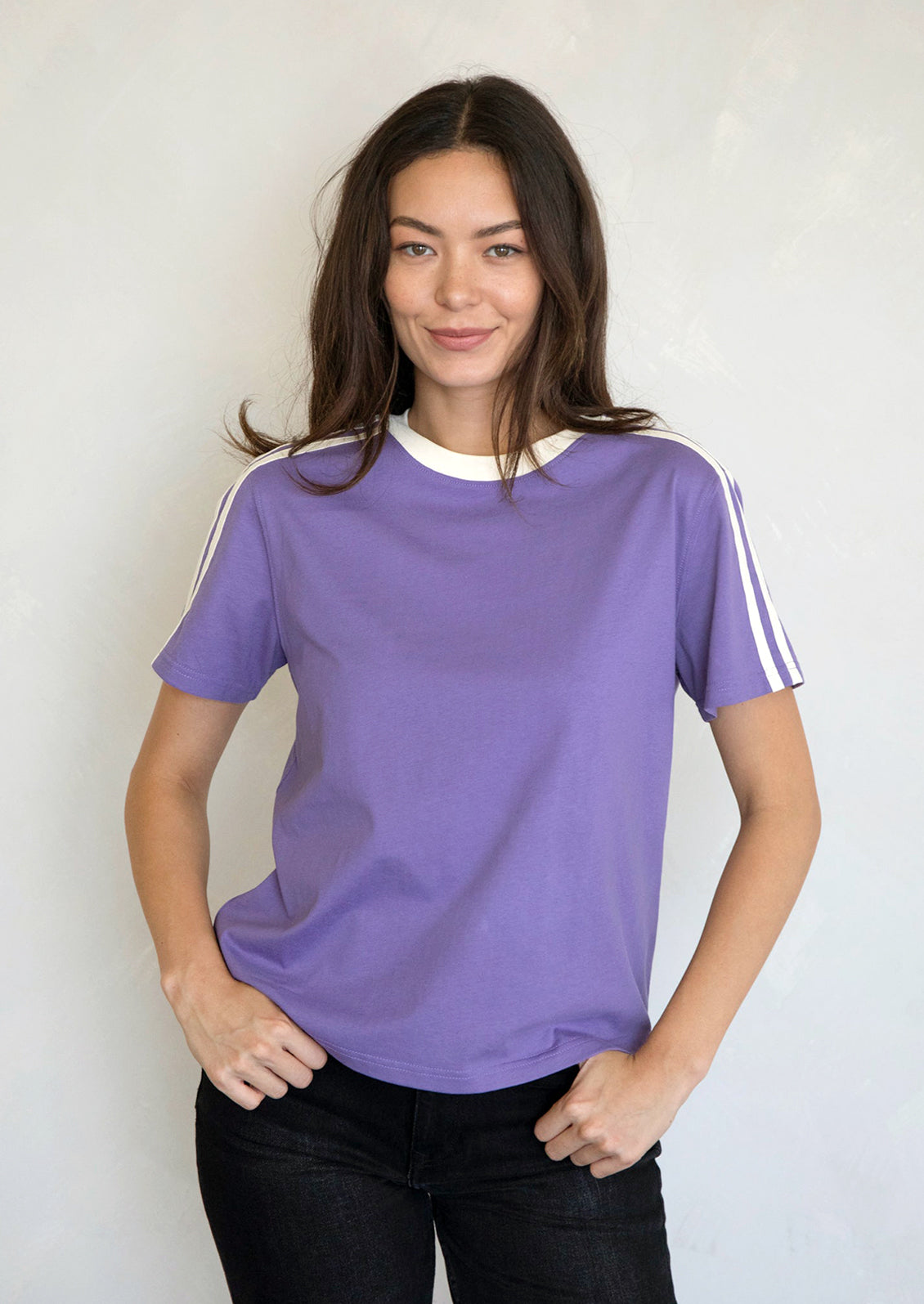 A woman wearing a purple t-shirt with white racing stripes at shoulders.