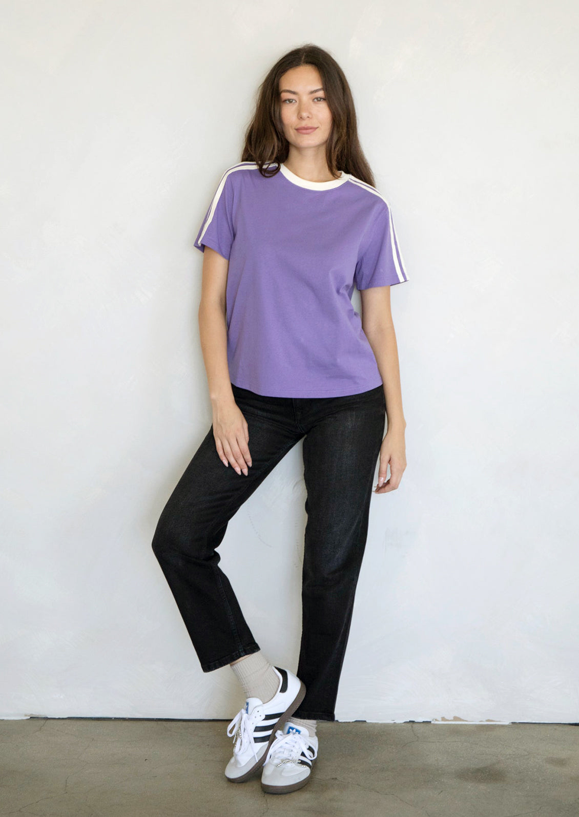 A woman wearing a purple t-shirt with white racing stripes at shoulders.