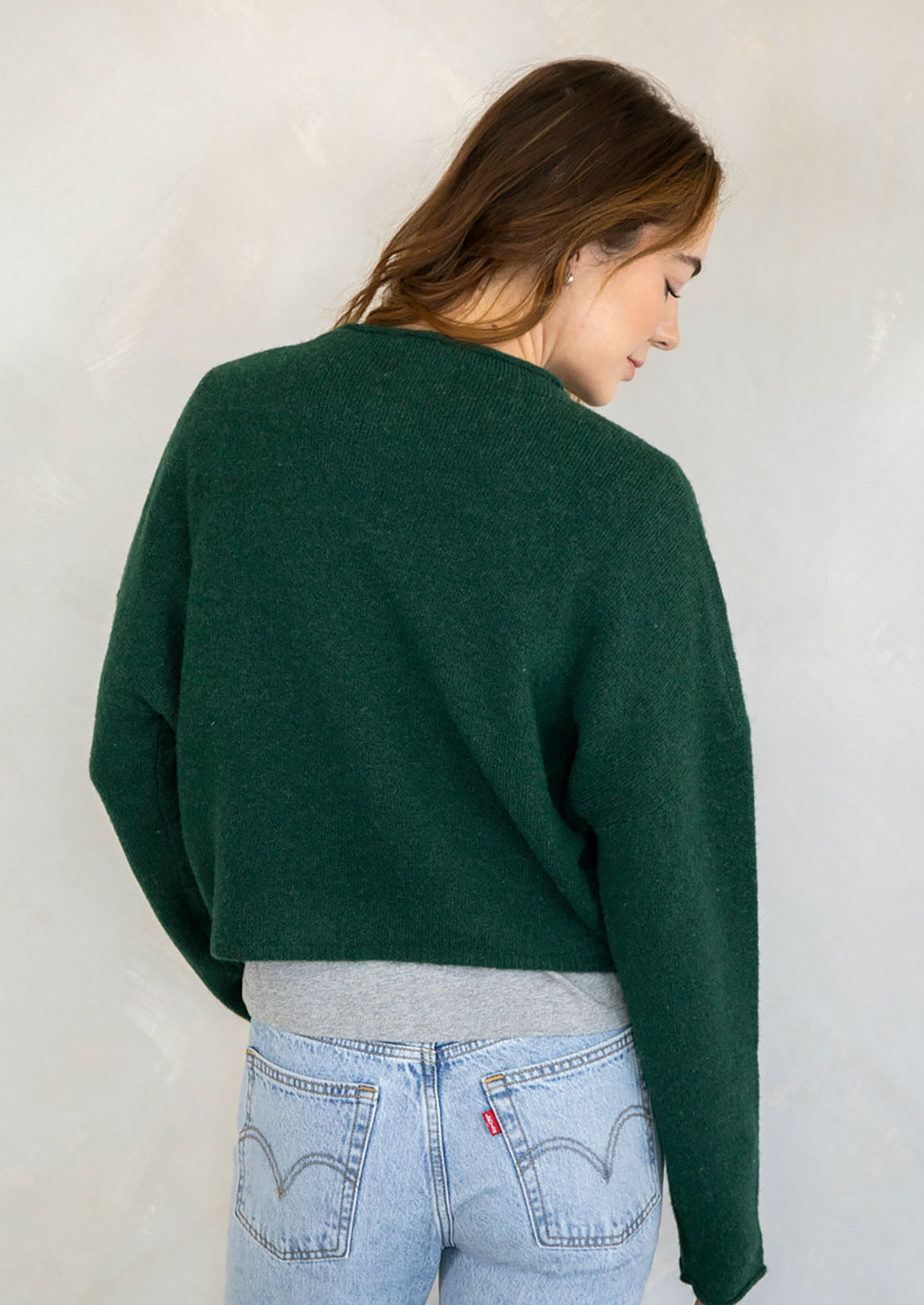 A woman wearing a forest green button front cardigan sweater.