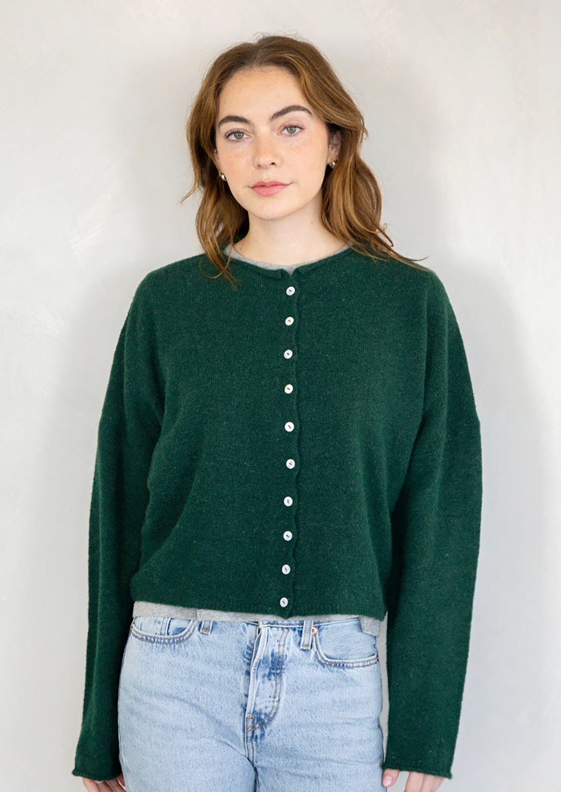 A woman wearing a forest green button front cardigan sweater.