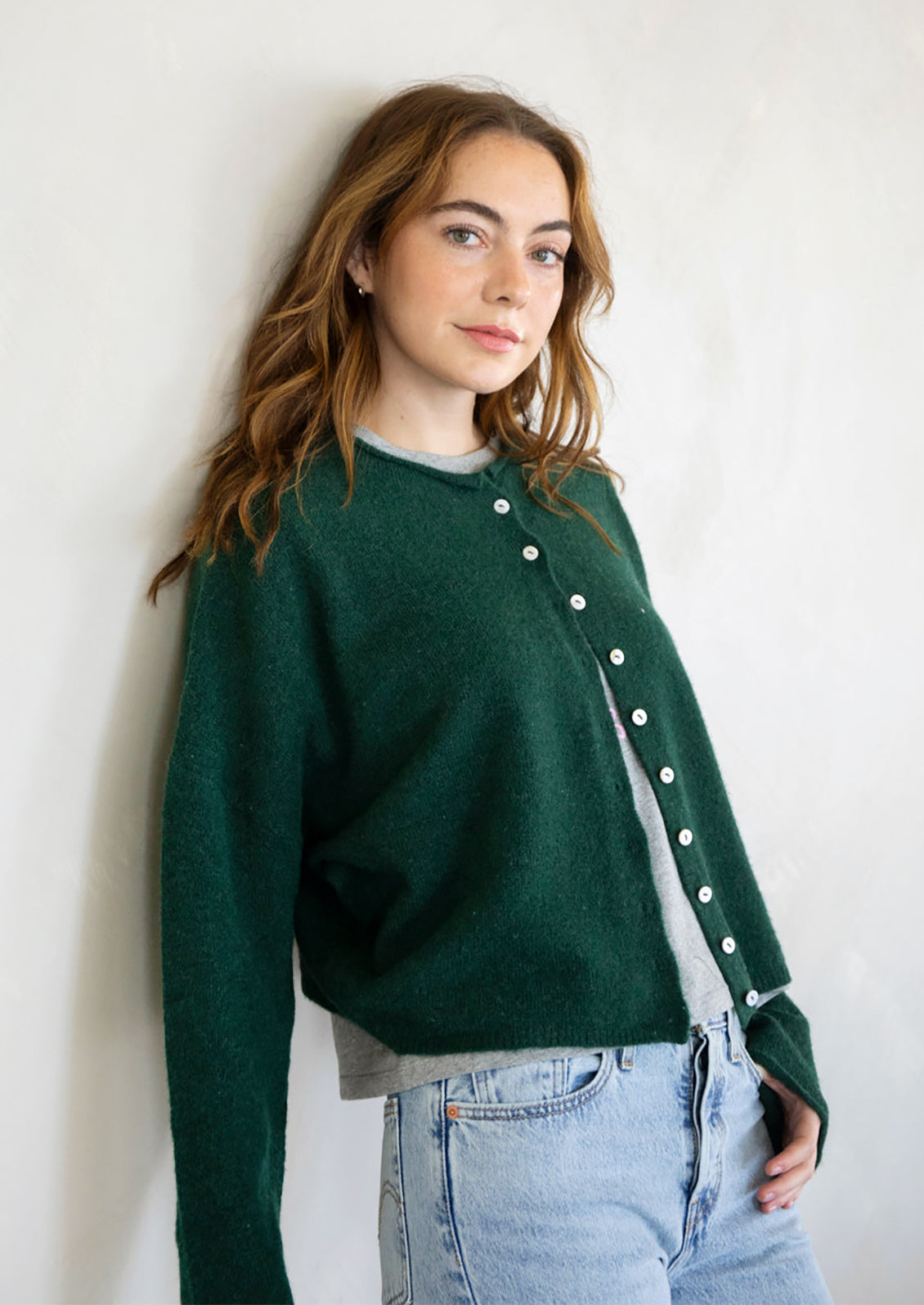 A woman wearing a forest green button front cardigan sweater.