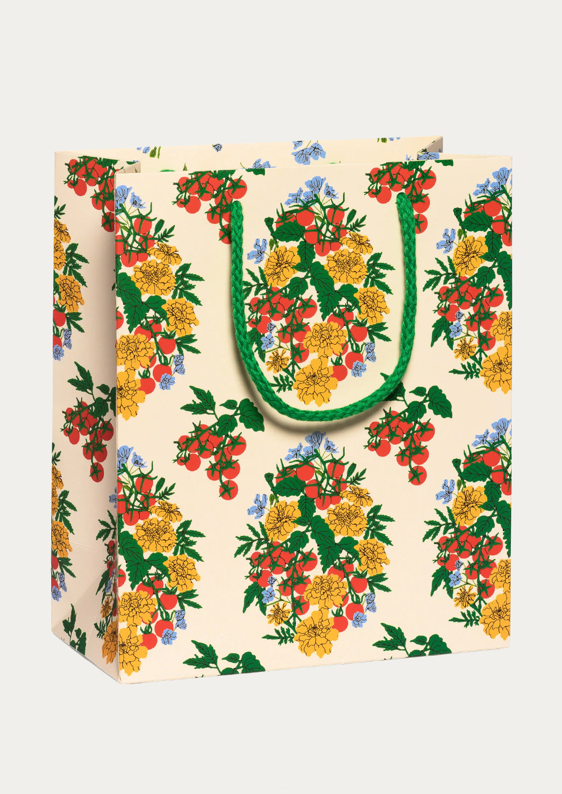 A cream-colored paper gift bag featuring a vibrant, repeating floral pattern of yellow marigolds, tomatoes, and blue wildflowers with green leaves. 