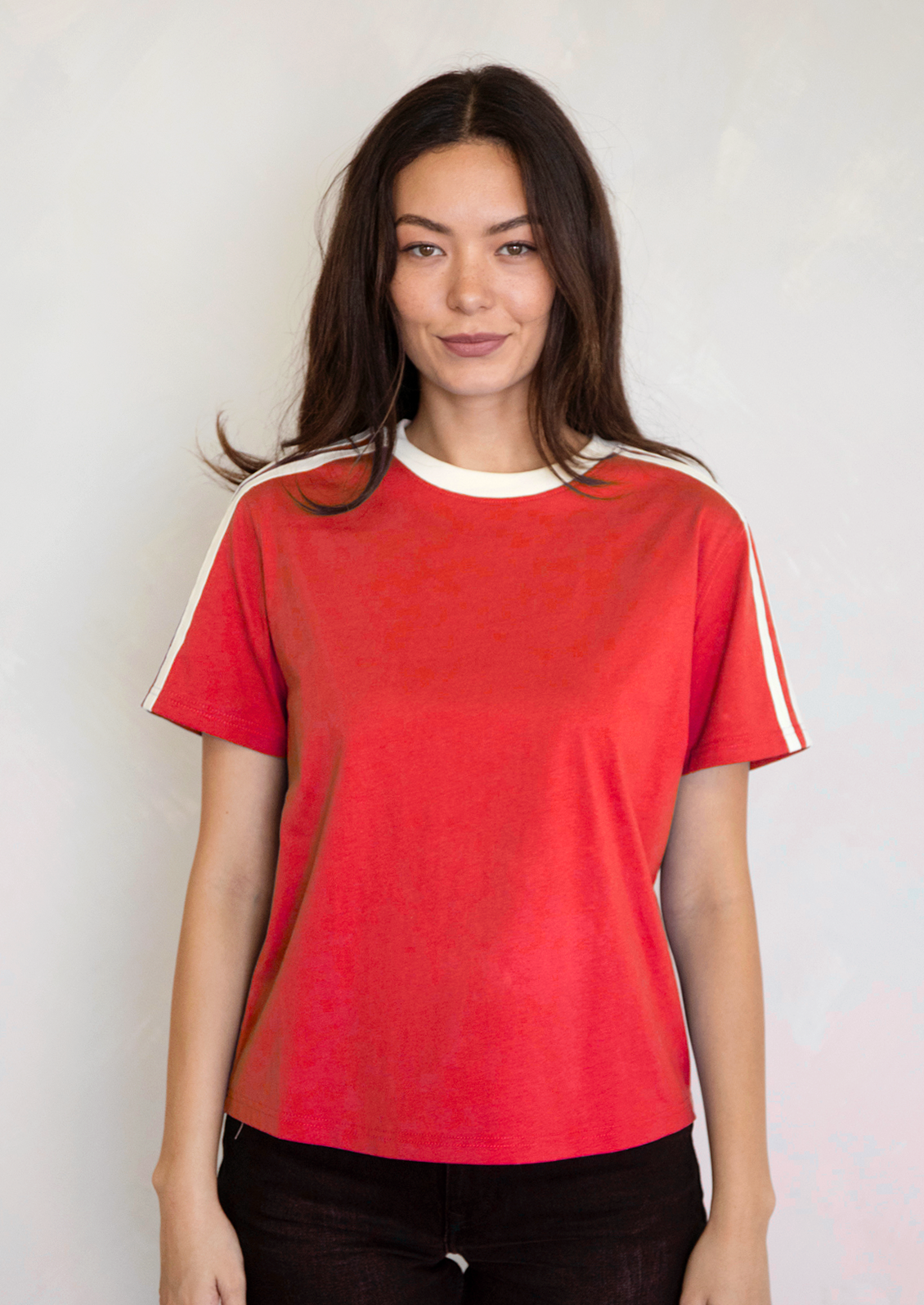 A woman wearing a red t-shirt with white racing stripes at shoulders.
