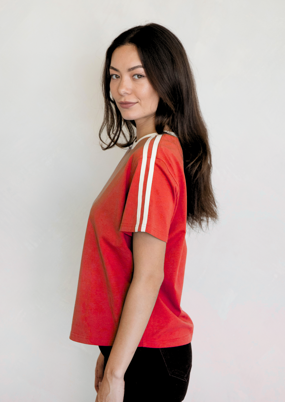 A woman wearing a red t-shirt with white racing stripes at shoulders.