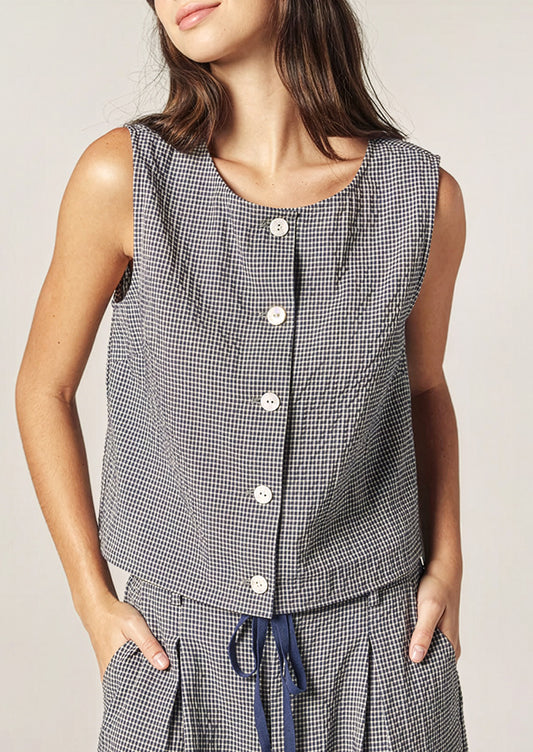 A person wearing a sleeveless shell top in navy and white gingham.