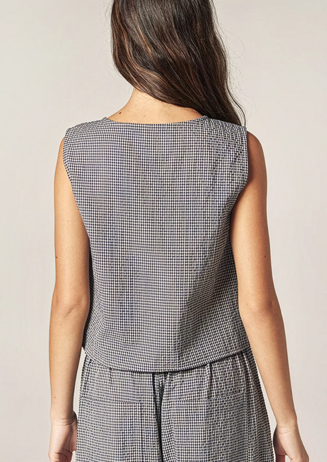 A person wearing a sleeveless shell top in navy and white gingham.