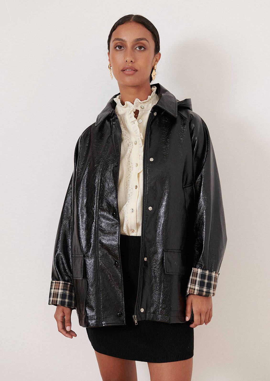 A woman wearing a patent jacket in black with plaid lining.