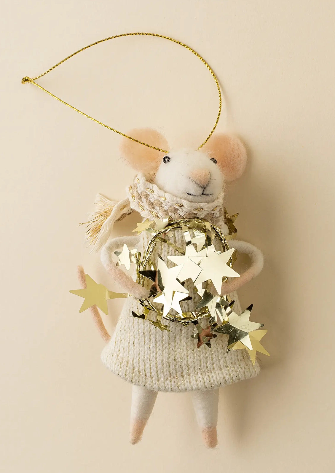A plush mouse Christmas ornament wearing a cream knit sweater and scarf, holding a gold star wreath, hanging from a gold wire loop against a warm beige background.