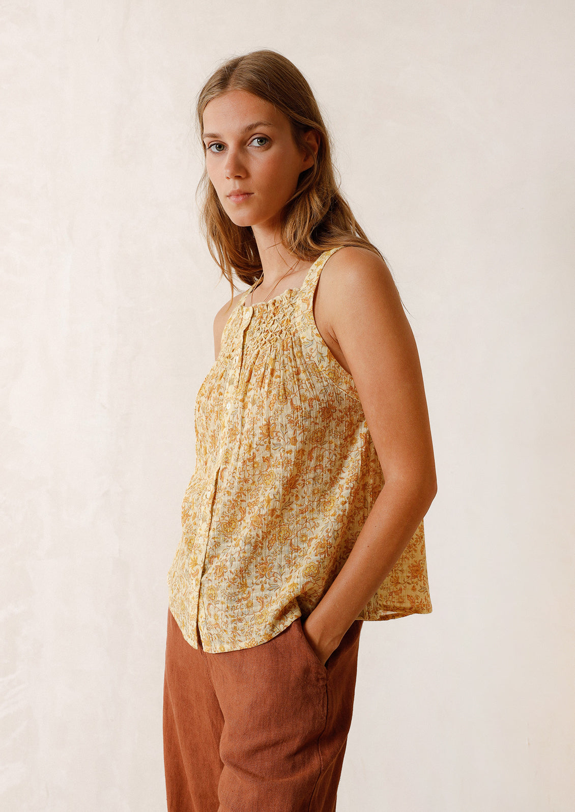A woman wearing a yellow floral print tank top.