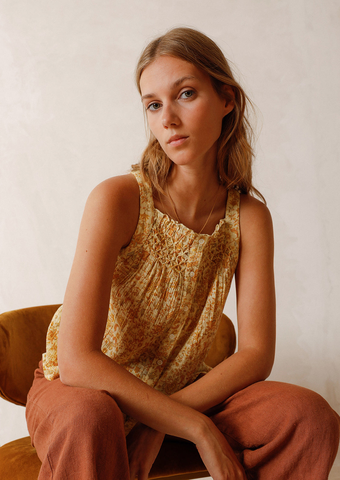 A woman wearing a yellow floral print tank top.