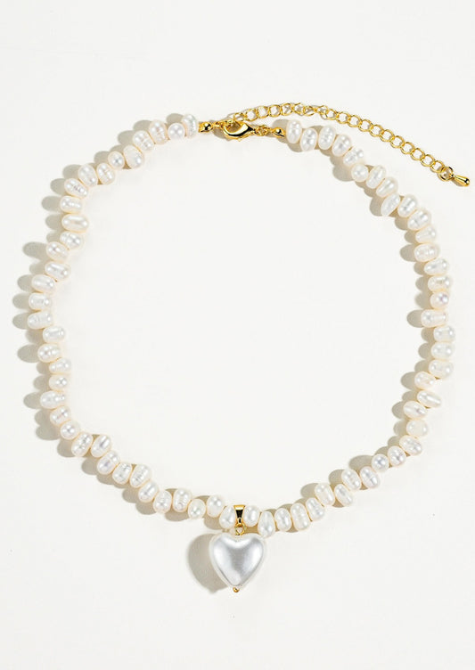 A white baroque pearl necklace with white pearlized heart shaped charm.
