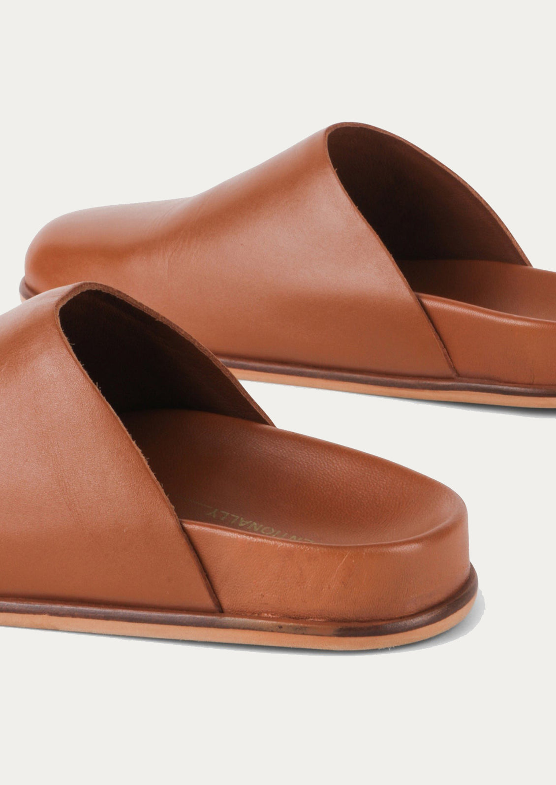 A pair of caramel leather closed toe slip-on mule shoes.