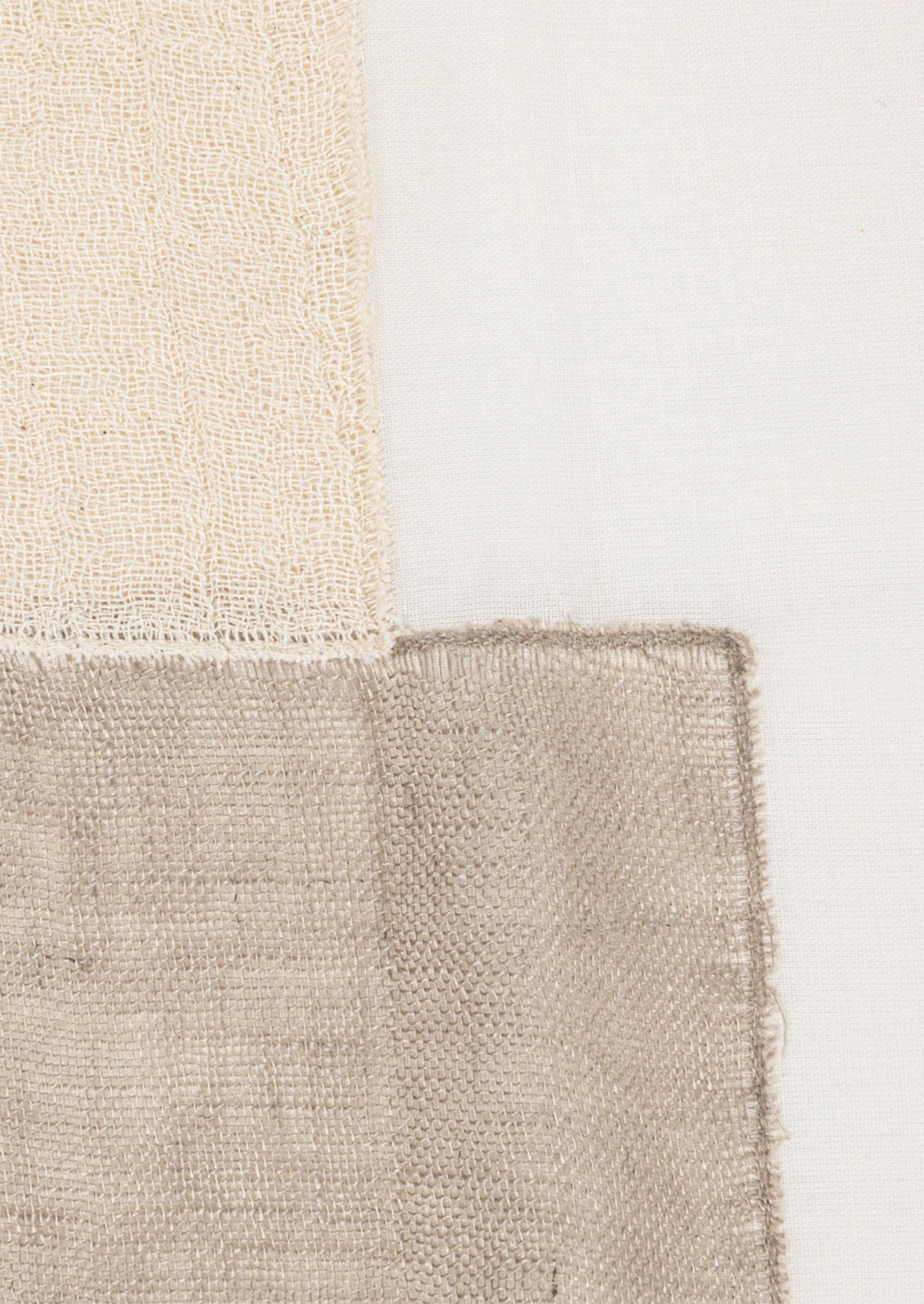 A throw pillow in sheer linen material with patchwork design in neutral colors.