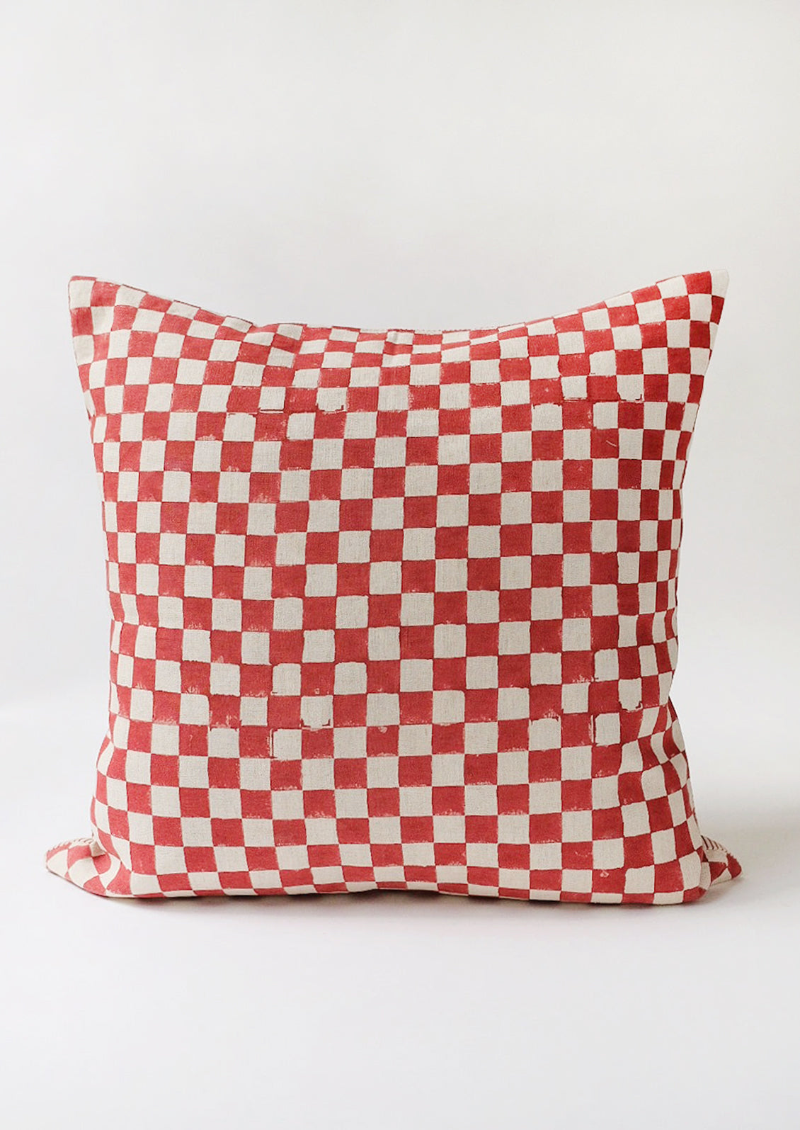 A block printed linen pillow in natural with ruby checker print.
