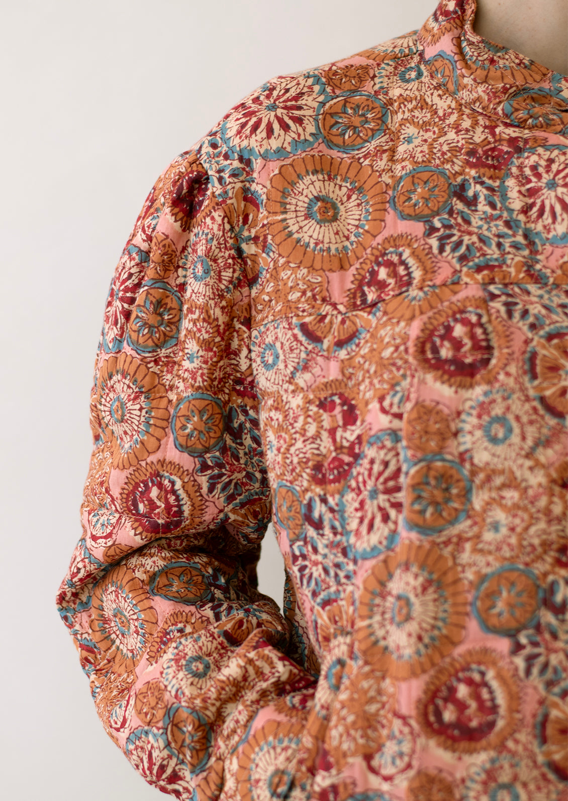 A woman wearing a cotton jacket in multicolor kaleidoscope print.