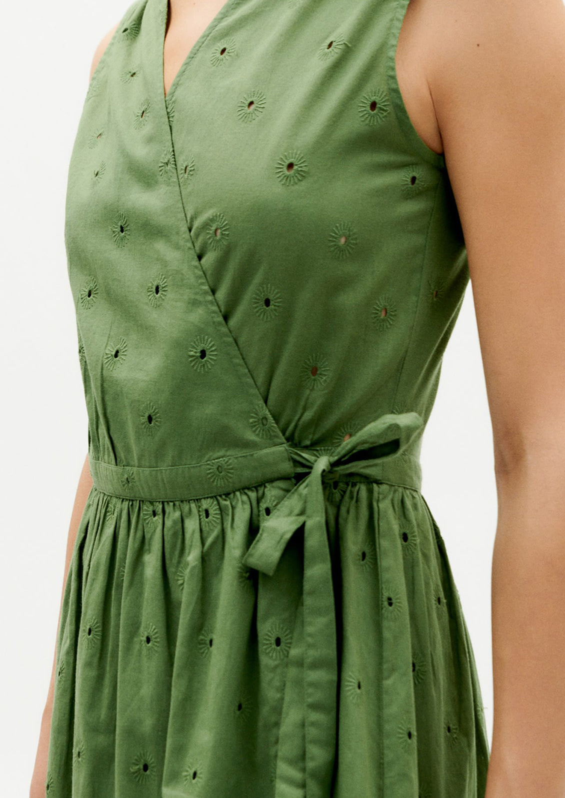 A woman wearing a green sleeveless midi wrap dress.