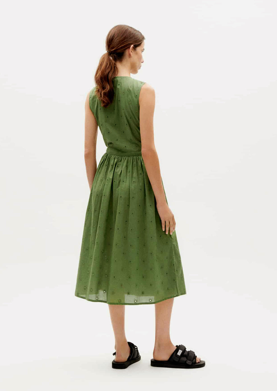 A woman wearing a green sleeveless midi wrap dress.