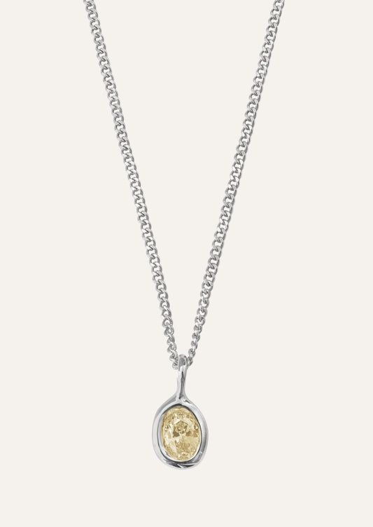 Silver necklace with an oval shaped pendant featuring a citrine colored gemstone.