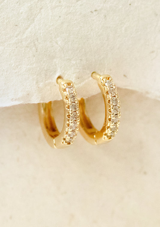 A pair of small huggie hoop earrings with cubic zirconia pave detailing.