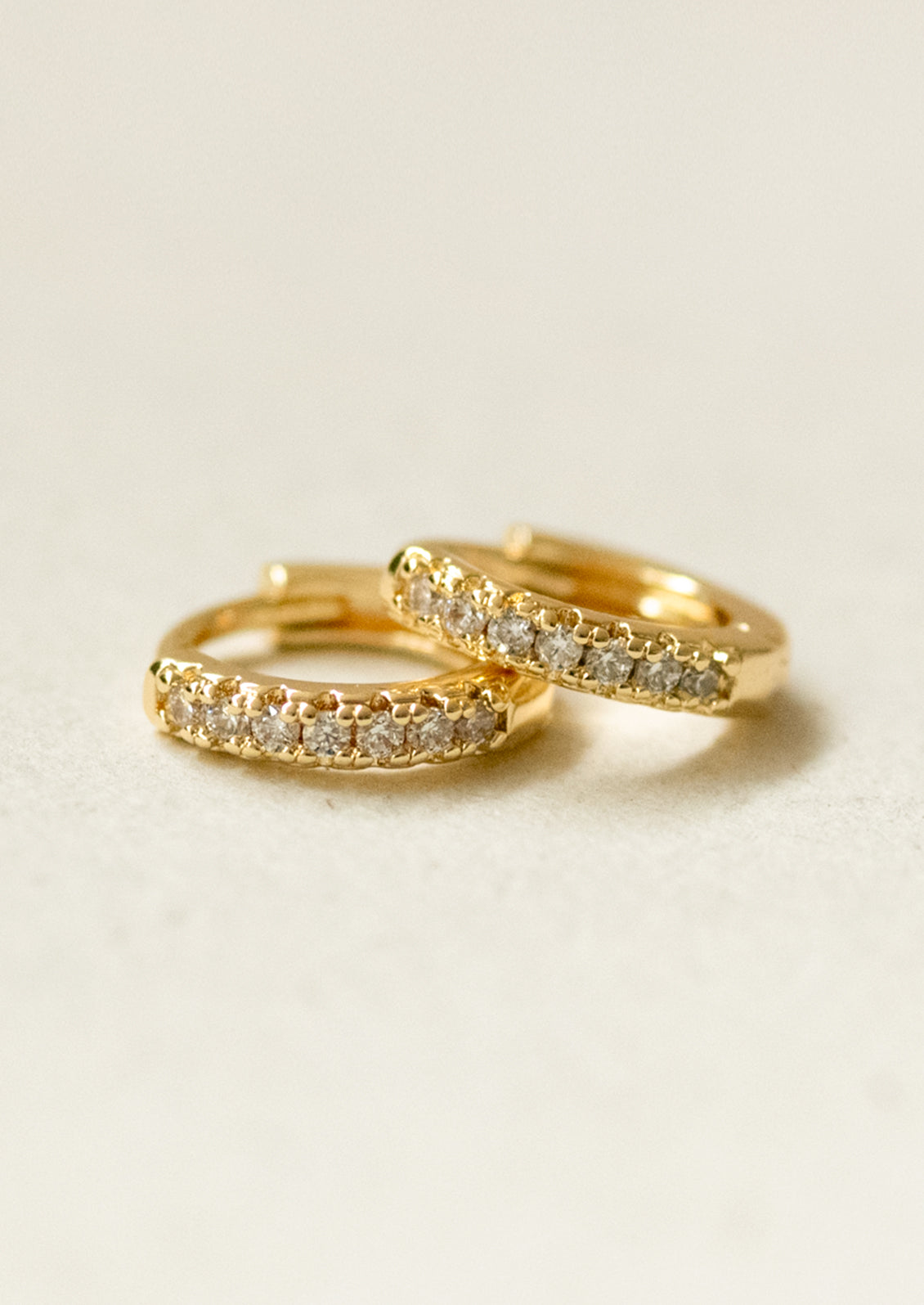 A pair of small huggie hoop earrings with cubic zirconia pave detailing.
