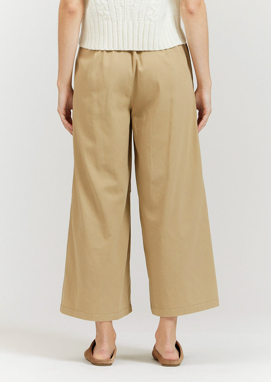 A pair of khaki colored wide leg pants with decorative knee pleat detail.