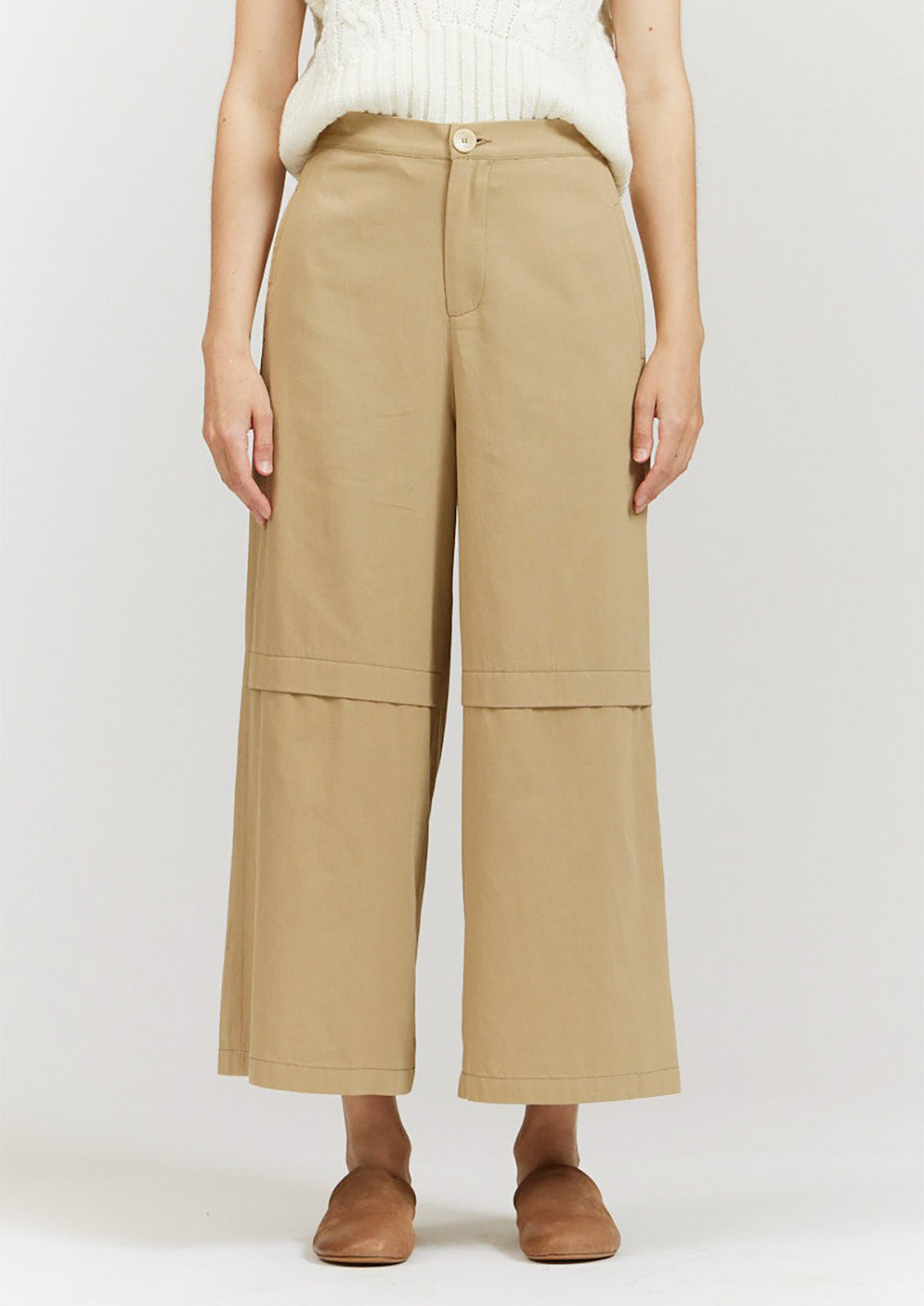 A pair of khaki colored wide leg pants with decorative knee pleat detail.