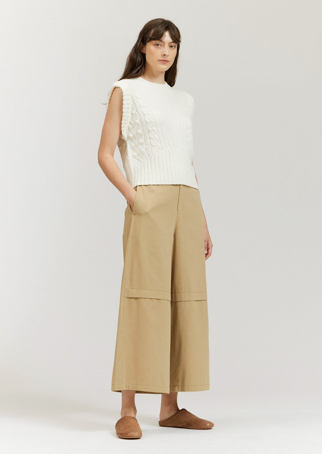 A pair of khaki colored wide leg pants with decorative knee pleat detail.