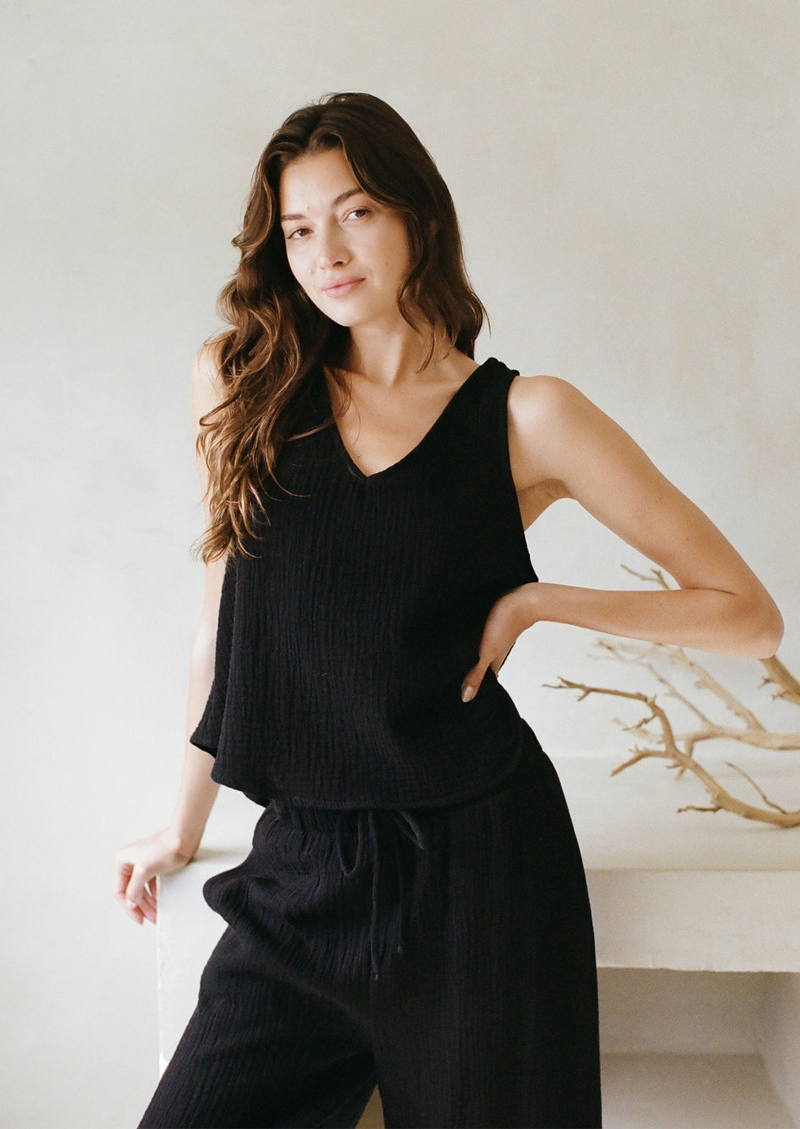 A woman in a black cotton gauze v-neck tank top. 